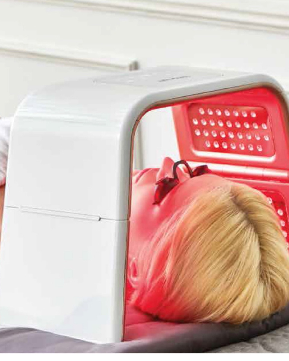 Client lying under the Omega Light LED dome glowing red
