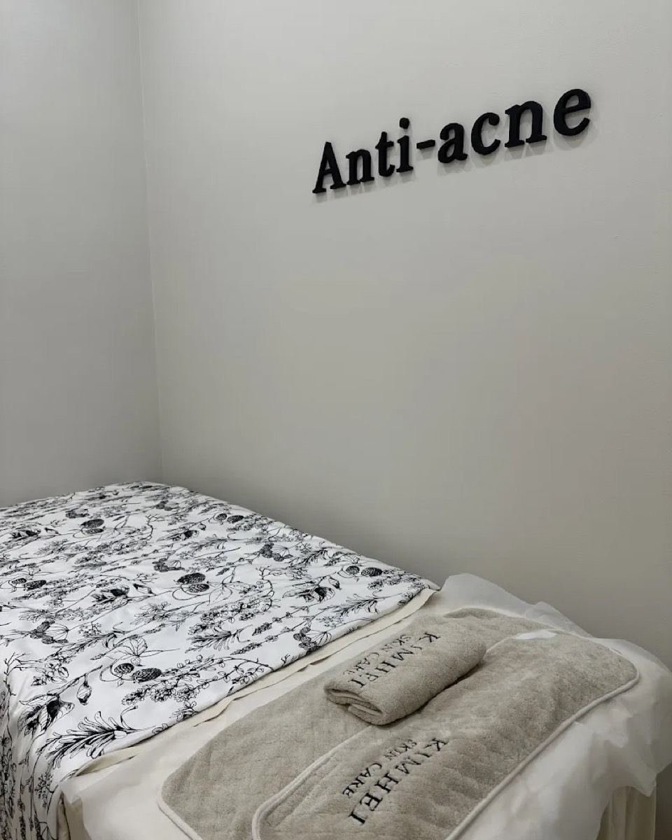 Anti-acne treatment room at KIMHEI with a made-up bed and towels
