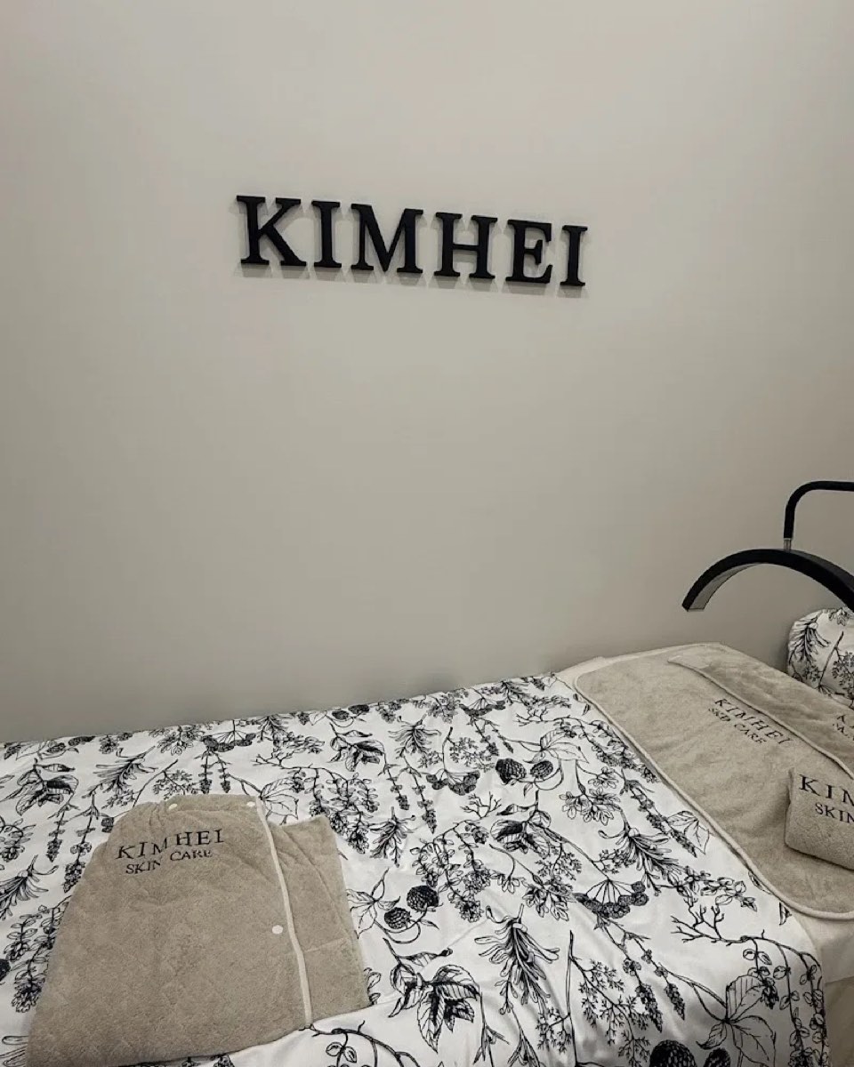 KIMHEI lettering above a made-up treatment bed with folded branded towels
