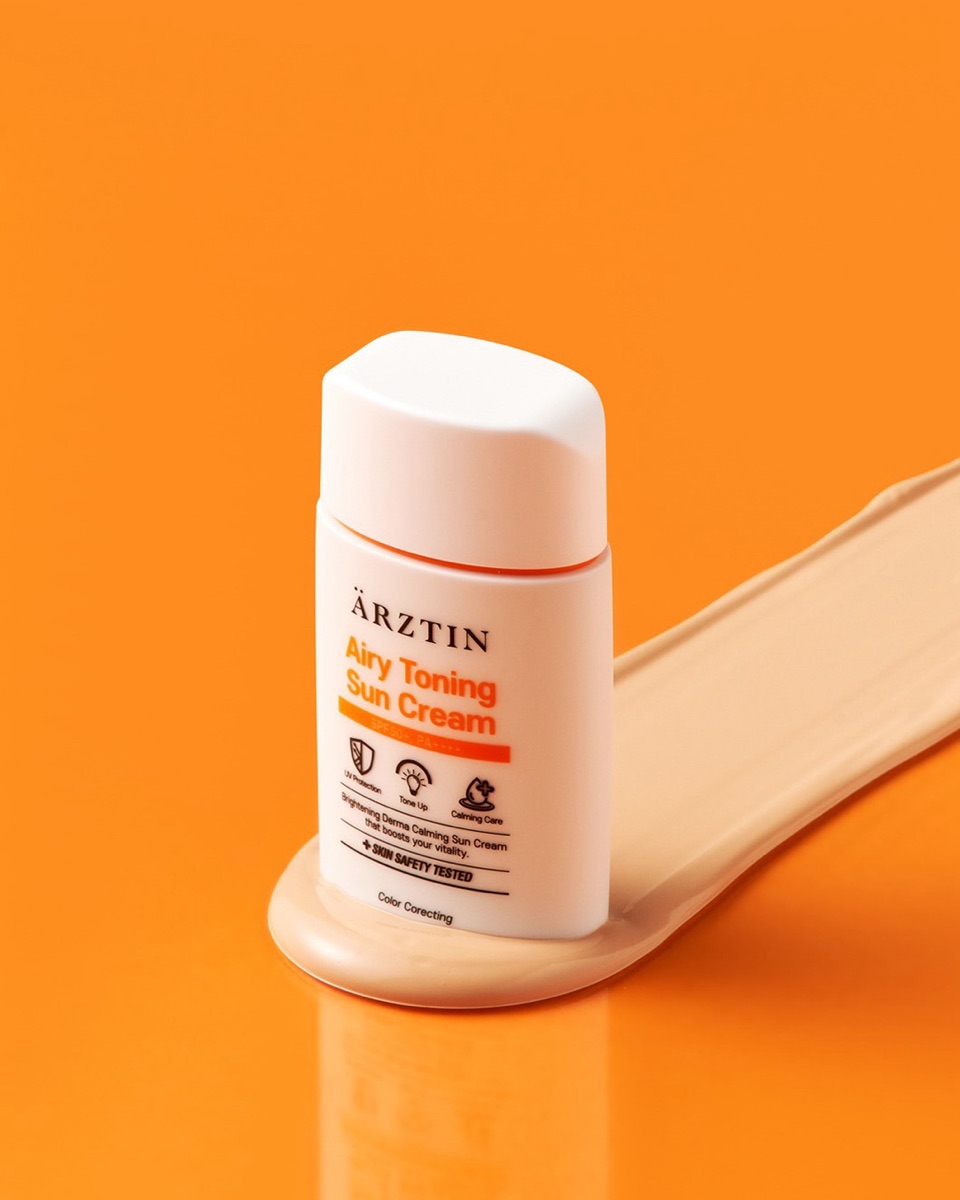 Ärztin Airy Toning Sun Cream SPF50+ tube on orange